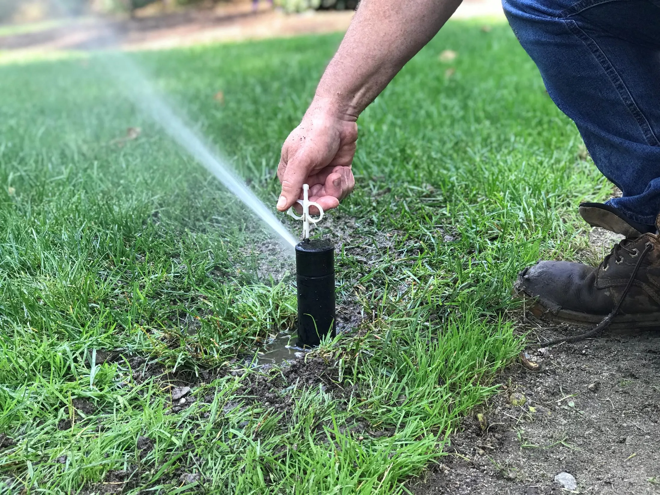 hand adjusting an lawn sprinkler head